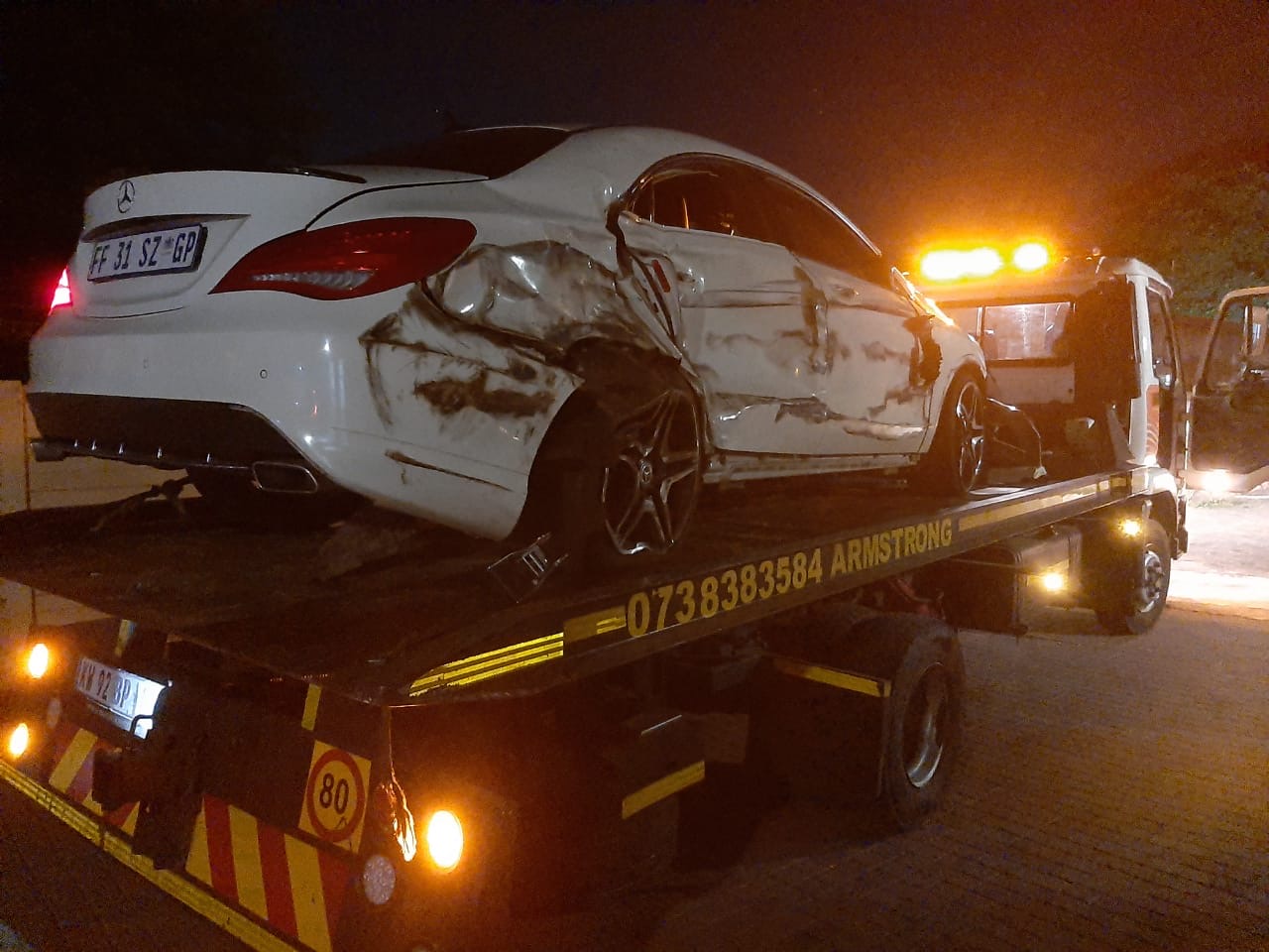 Armstrong Towing loading a damaged Mercedes onto the flatbed tow truck at night