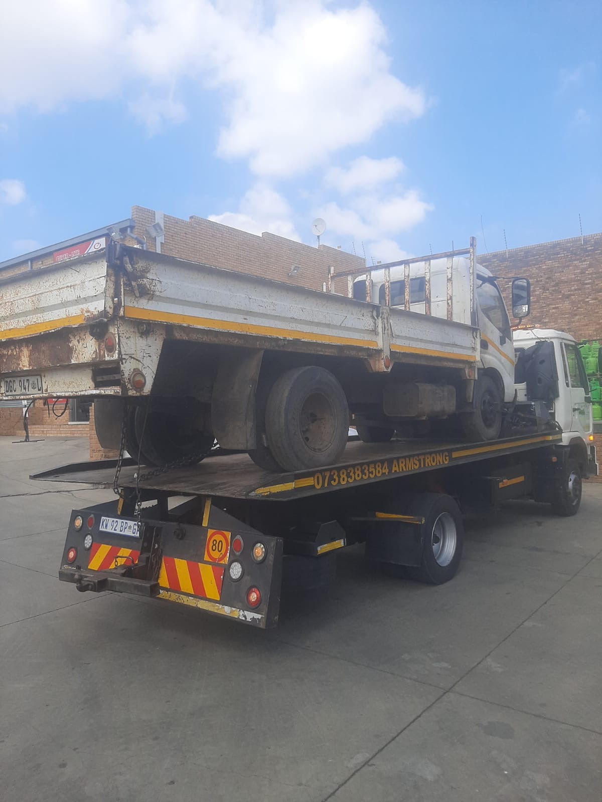 A flatbed cargo truck being carried on the Armstrong Towing rollback